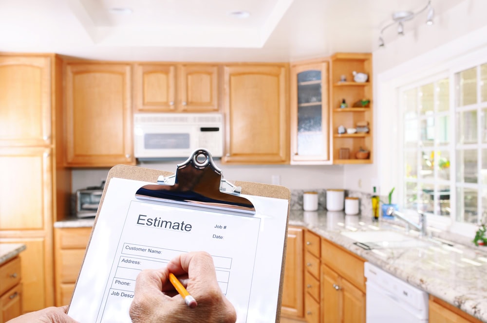A person holding a clipboard with a construction estimate form in a bright kitchen setting.
