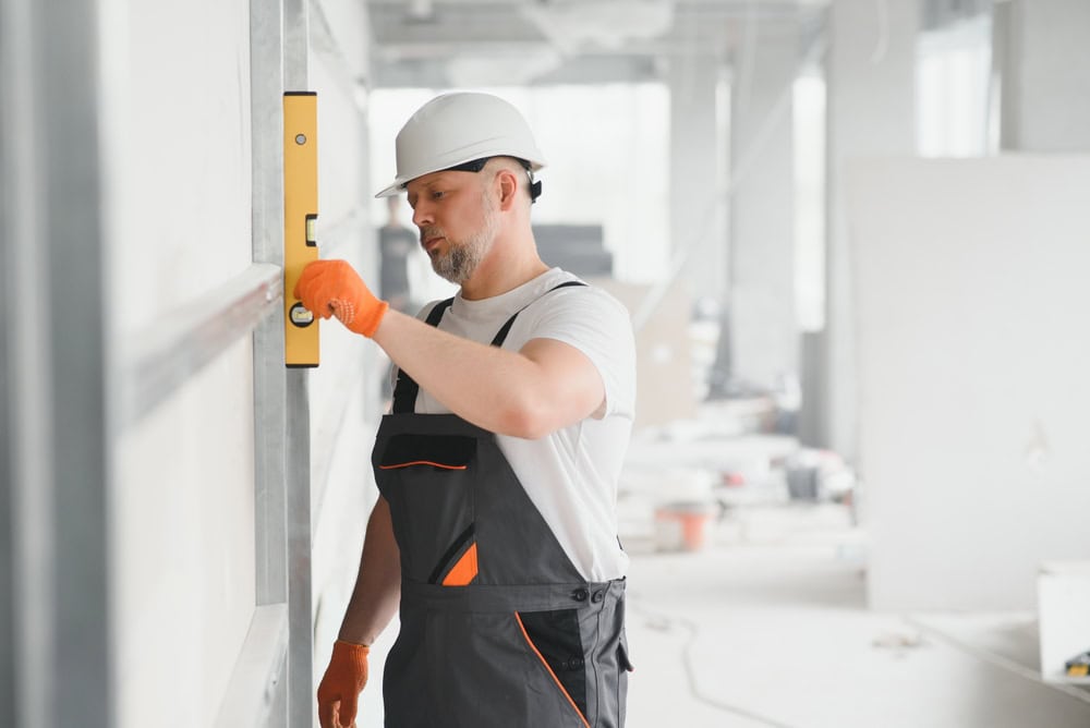 Skilled construction worker installing a level on a wall at a commercial building site.