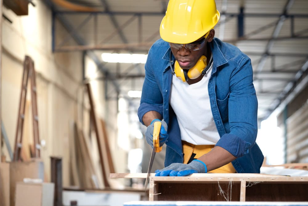 Professional carpenter measuring wood in a workshop, highlighting construction skills and craftsmanship.