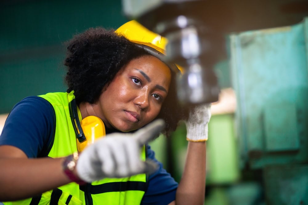Professional woman in construction gear inspecting equipment on site.