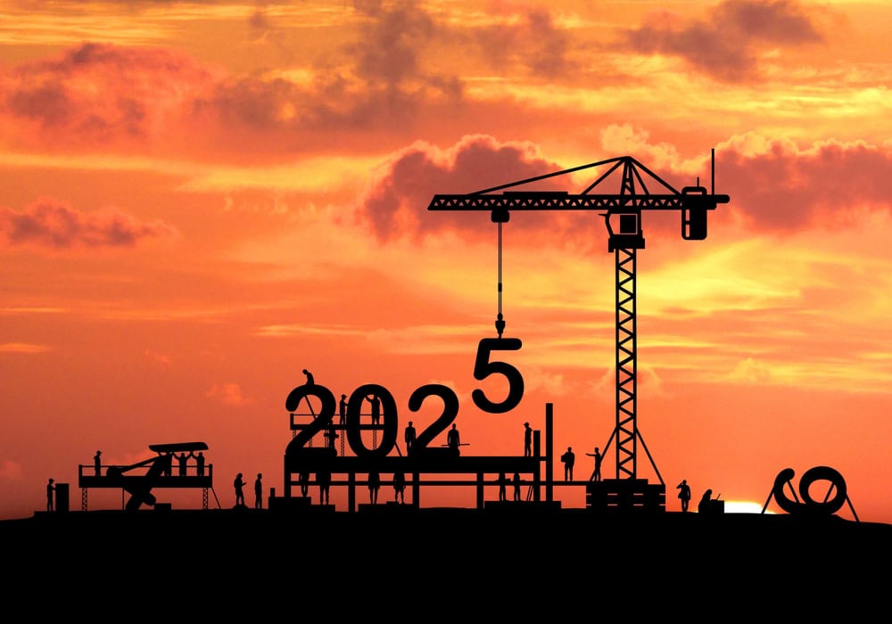 Construction crane silhouette against a colorful sunset sky with the year 2025 and building workers at a construction site.