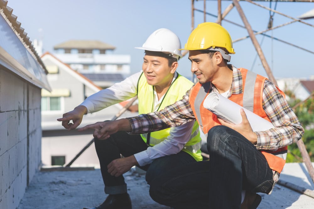Construction workers inspecting a building site, wearing safety gear and discussing project details on a sunny day.