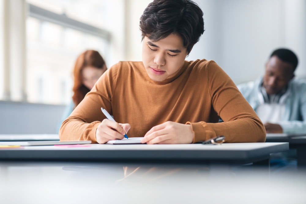 Young man taking a written exam in a classroom, participating in contractor licensing education or certification.