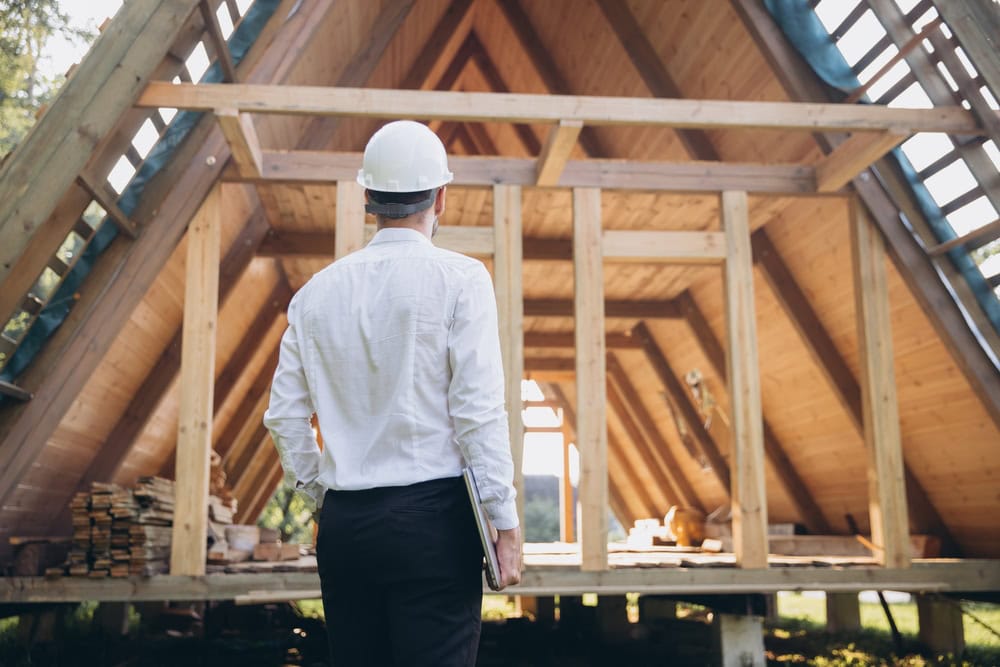 Construction site of a new home with a worker inspecting the wooden frame during the building process.