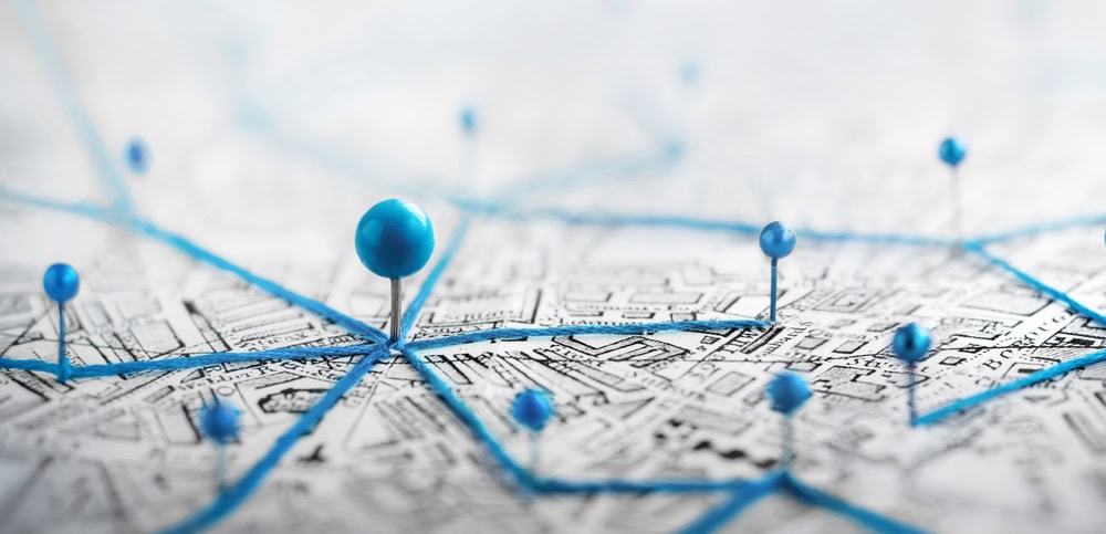 Pin with multiple blue push pins securing a detailed city map on paper.