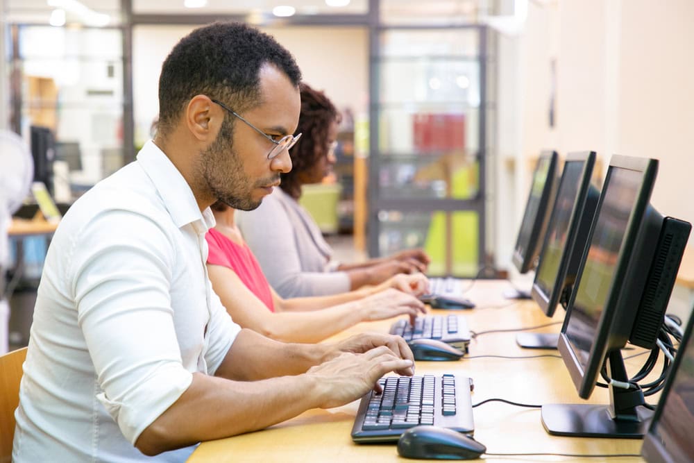 Professional adults working on computers in a busy office environment.