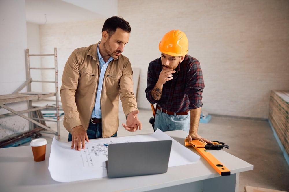 Professional construction workers reviewing blueprints at a construction site.