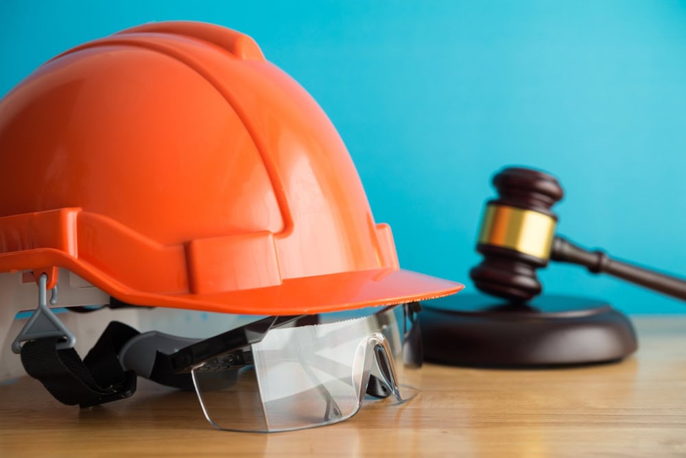 Orange construction helmet with safety glasses and a gavel, symbolizing contractor licensing and legal authority in construction.