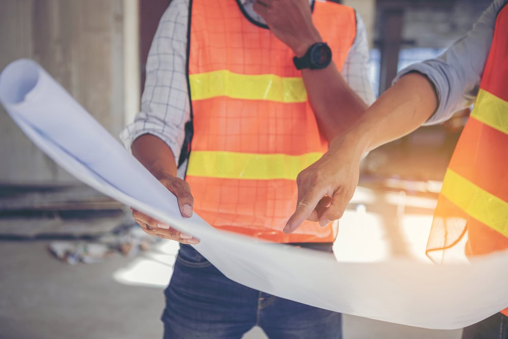 Construction workers reviewing blueprints at a building site.