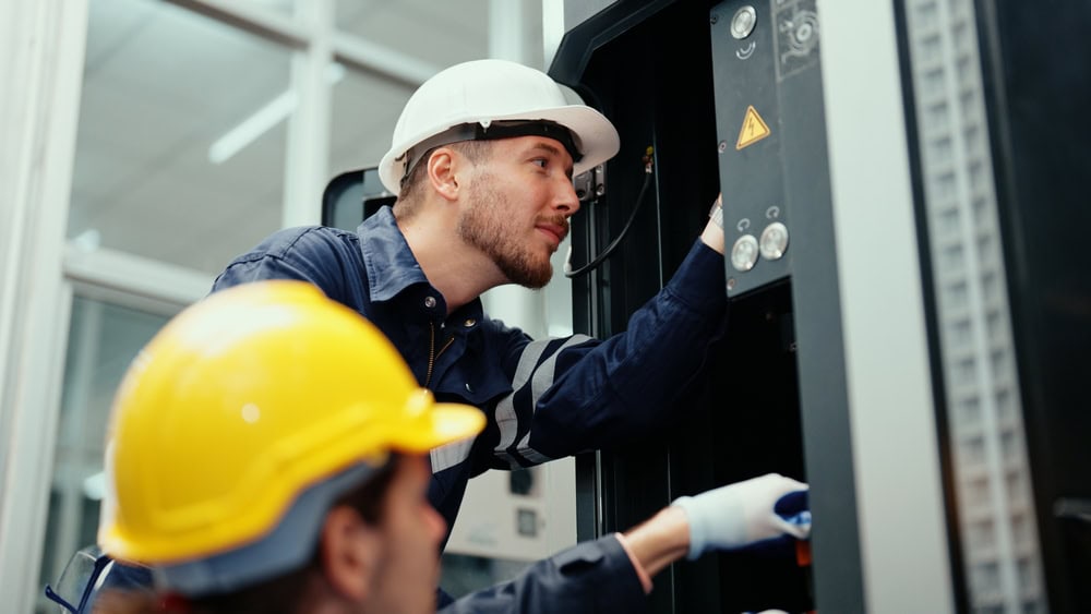 Technicians working on electrical panels in a modern industrial setting; hands-on training for aspiring electrical contractors for licensing and certification.