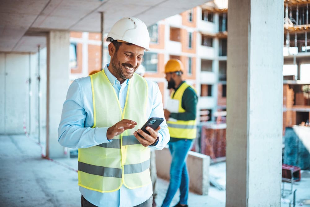 Construction worker using a smartphone on a building site.