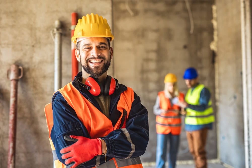 Experienced construction worker wearing safety helmet and vest at a construction site.