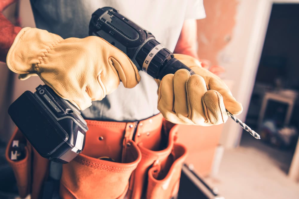 Power drill in handyman’s gloves for construction work.