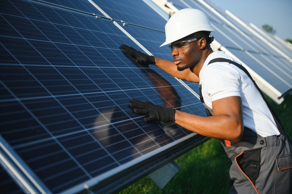Installing solar panels on a sunny day for renewable energy, with a worker inspecting solar power systems.