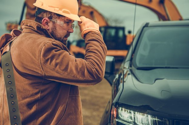 Construction worker inspecting vehicle at construction site.