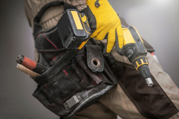 Battery-powered drill and construction tool belt for contractors, highlighting essential equipment for trade professionals.