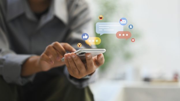 Efficient social media communication with chat bubbles and emojis floating above a smartphone.