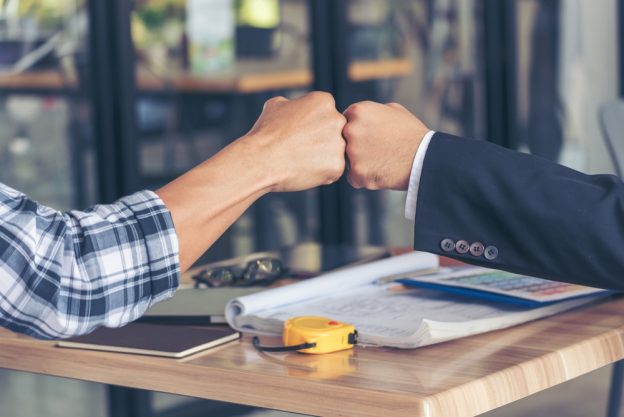 Fist bump of two professionals symbolizing partnership and success in the contracting industry.
