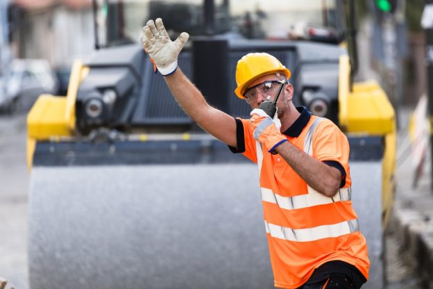 Busy construction worker giving direction on site in safety gear.
