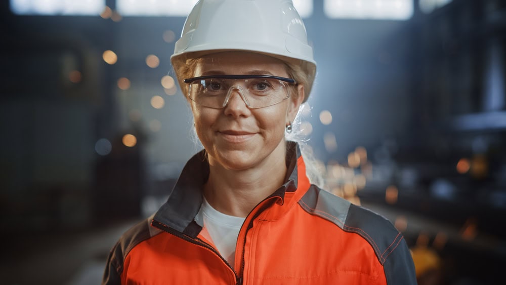 Welding female worker in safety gear at industrial workshop.
