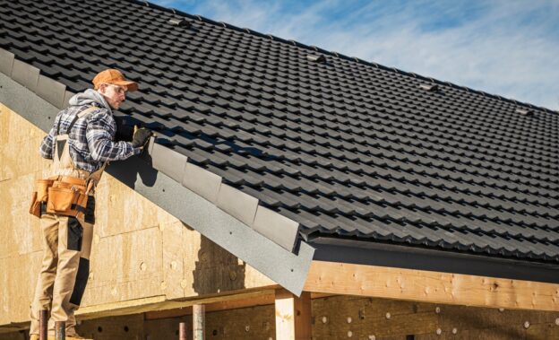 Roofing contractor inspecting roof installation on a residential building.