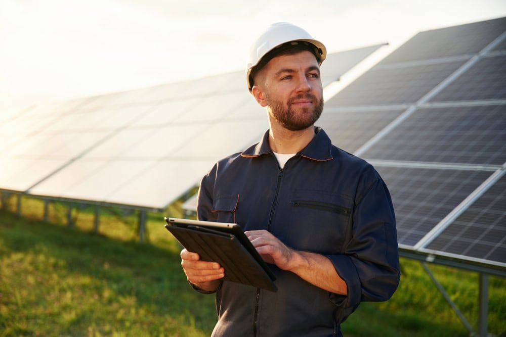 Solar panel technician inspecting solar installation outdoors.