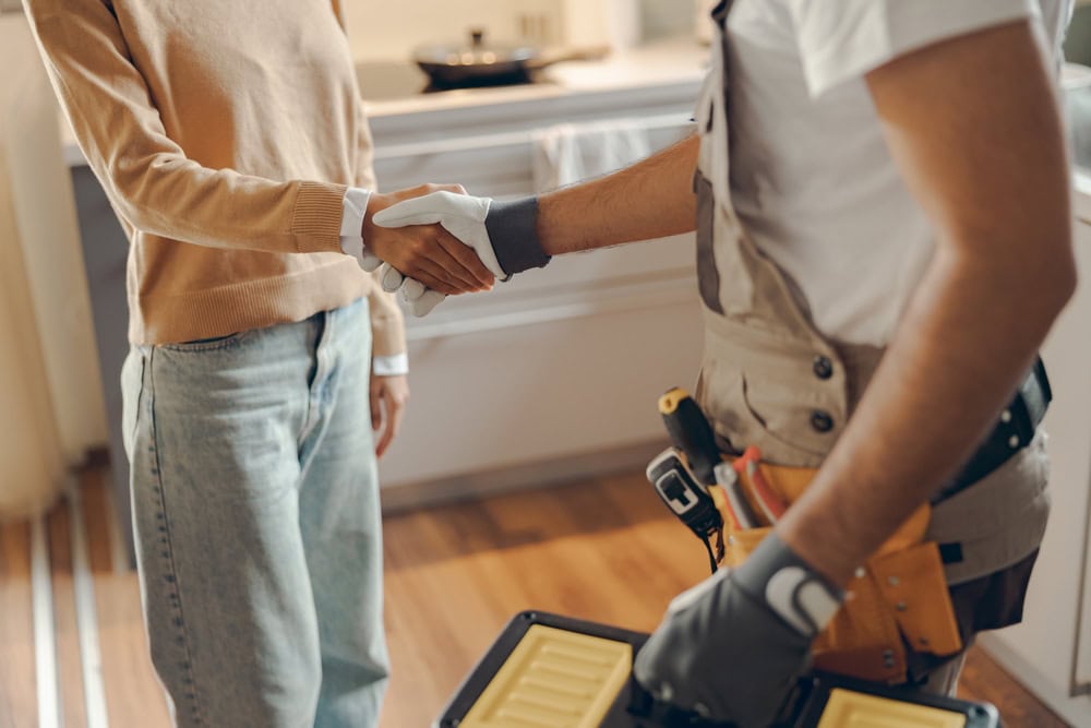 Contractor and client shaking hands in a home renovation setting, emphasizing trust and professionalism in the construction industry.