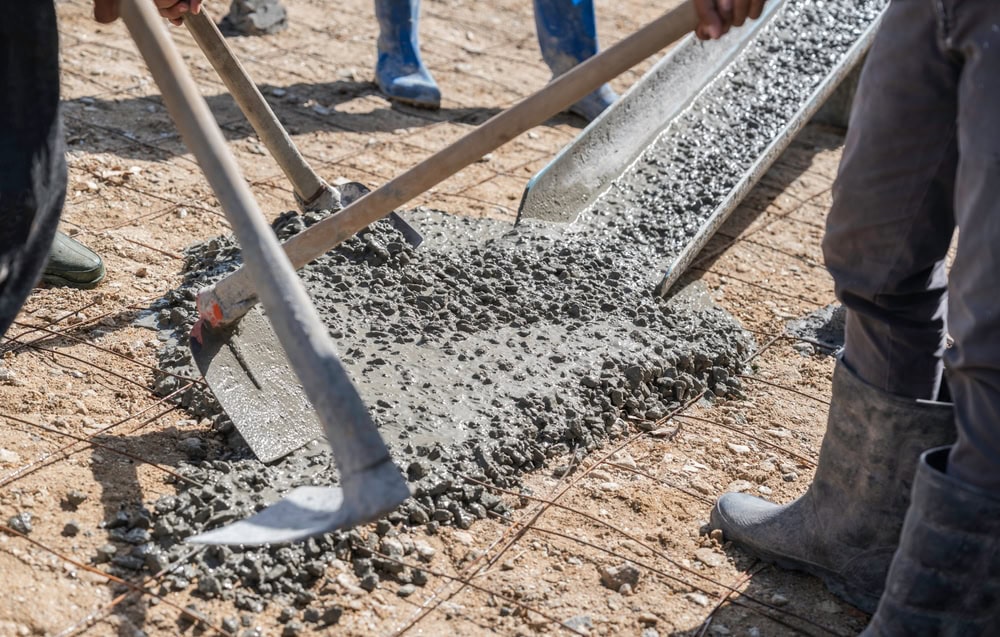 Workers pouring and spreading concrete on a construction site for building or infrastructure projects.
