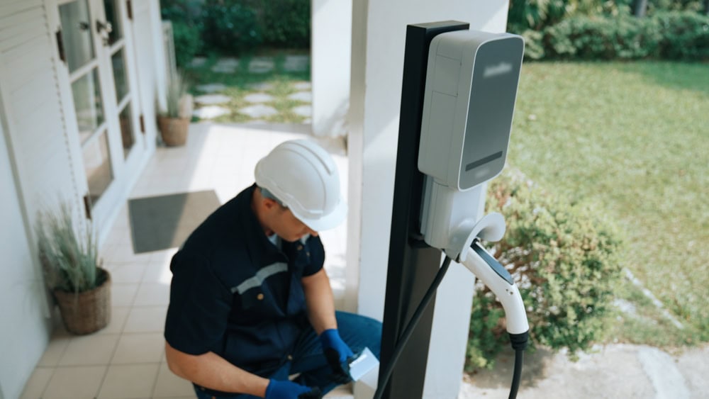 Electrician installing a charging station outdoors, emphasizing electrical work and contractor skills for licensing and certification.