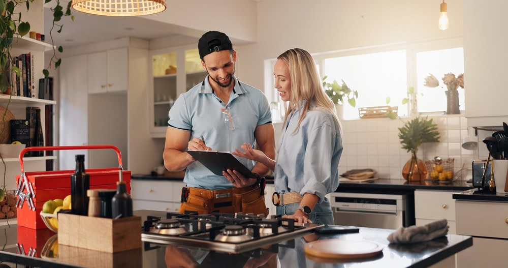 A contractor and a woman discussing plans in a modern kitchen, emphasizing home renovation and construction services.